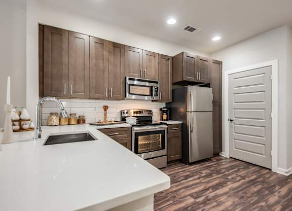 A modern kitchen with brown cabinets and stainless steel appliances.