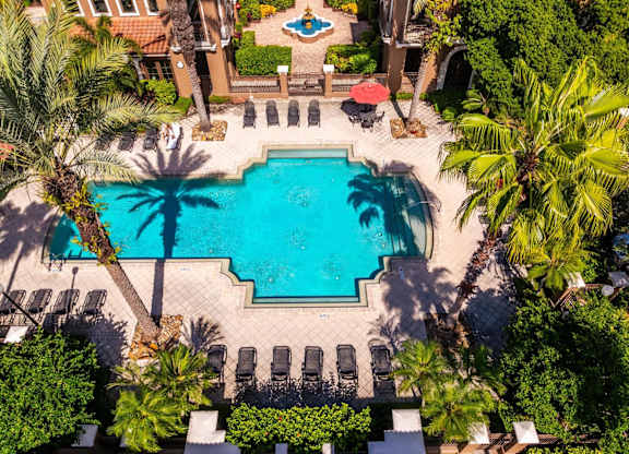 Overhead view of Mediterranean-style clubhouse and pool with palm trees