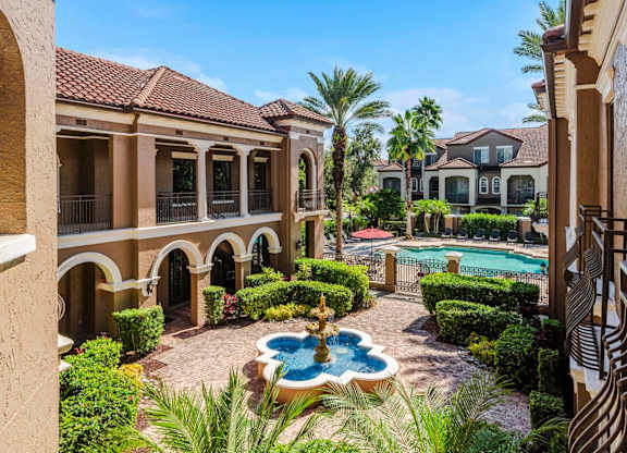 Courtyard fountain leading to the resort-style pool and palm-lined architecture.