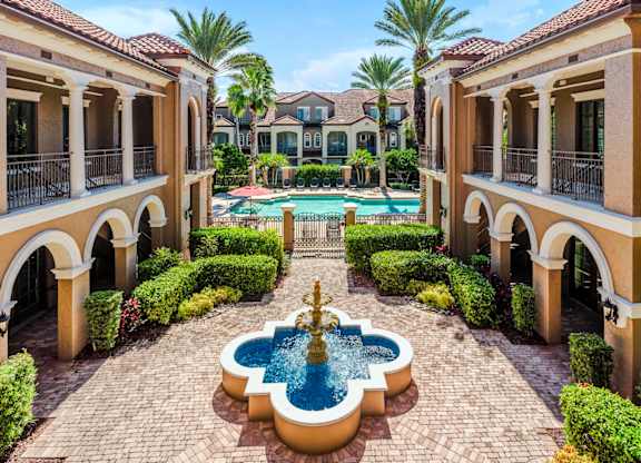 Tranquil courtyard fountain framed by palm trees and Mediterranean-style architecture.