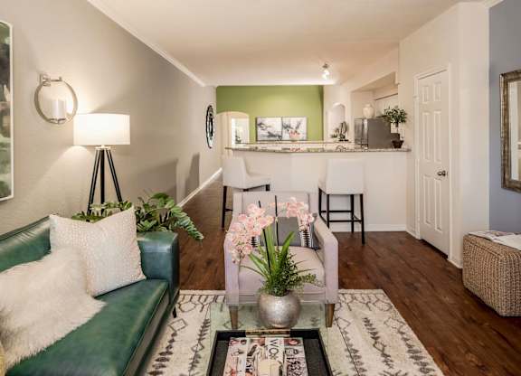 Open living area with bar seating and wood floors leading to the kitchen