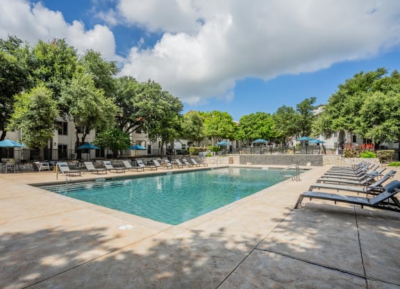 a resort style pool with lounge chairs and trees