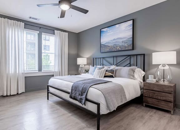 Spacious primary bedroom with dark gray walls and ceiling fan at Novel Cary