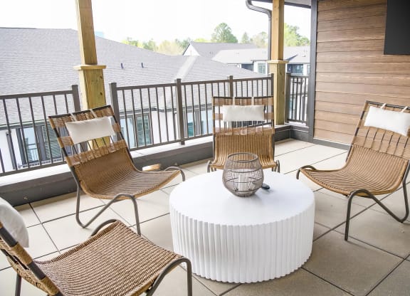 Cozy balcony with wicker style chairs and large flatscreen television at Novel Cary