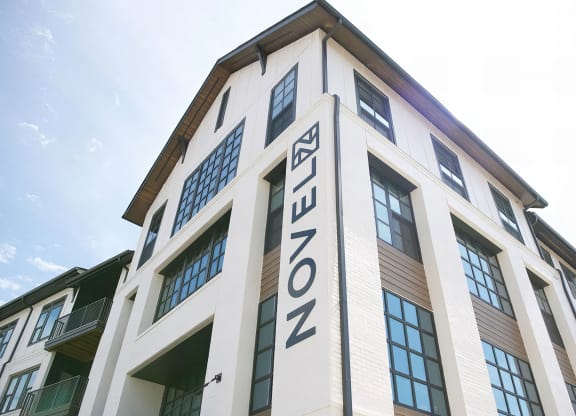 Modern apartment buildings with white bricks, wood accents, and dark window frames at Novel Cary