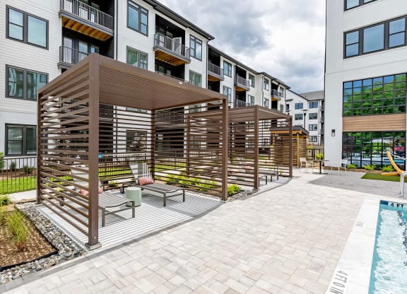 Sophisticated outdoor pool area with cabanas and lounge chairs at Novel Cary