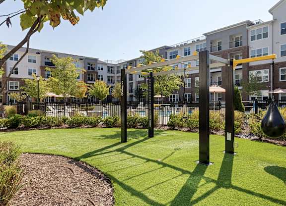A playground with a swing set and a slide in the foreground and apartment buildings in the background.