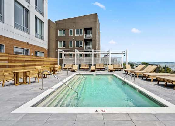 A large outdoor swimming pool with loungers and a white fence.