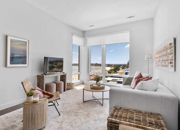 A living room with a grey couch, a wooden table, and a painting on the wall.