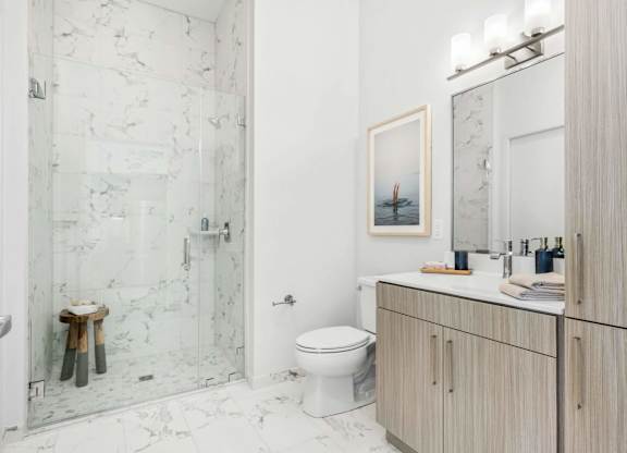 A bathroom with a toilet, sink, and a picture of a boat on the wall.