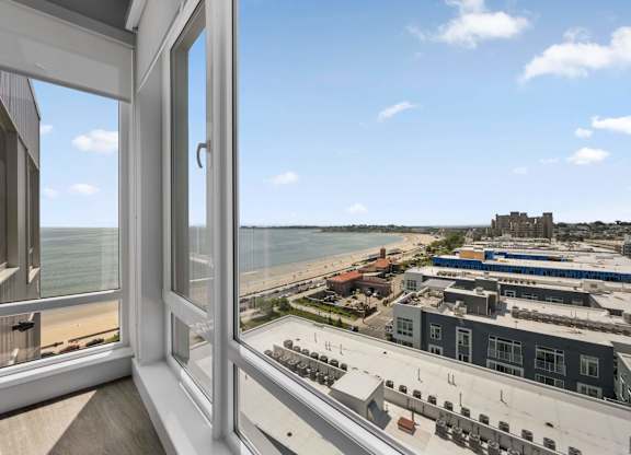 A view from a window looking out to a beach and buildings.