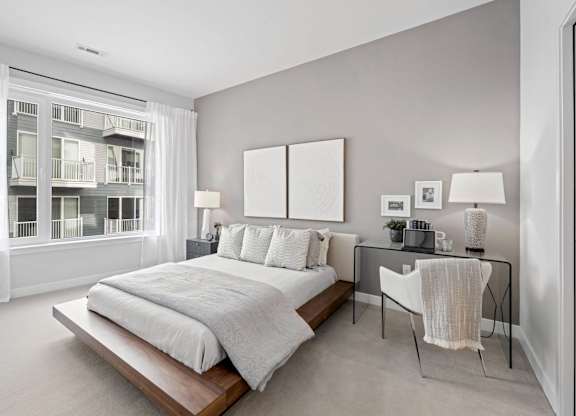 A bedroom with a large bed and a desk with a chair.
