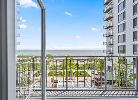 A balcony with a view of the ocean and a building in the distance.