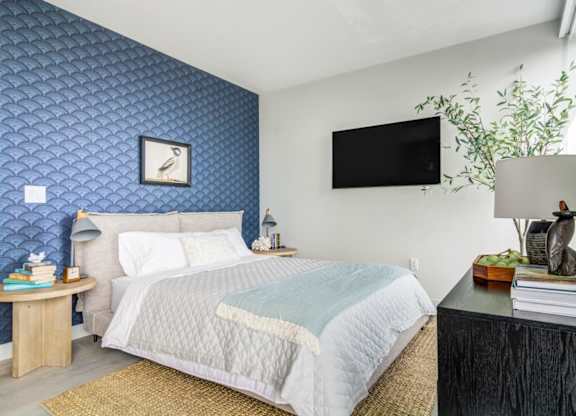 A bedroom with a bed, nightstand, and a wall clock.