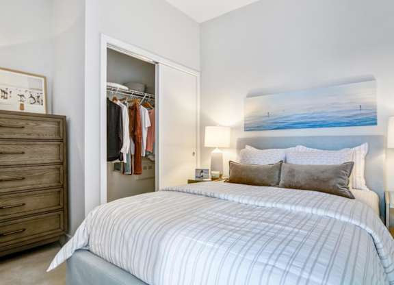 A bedroom with a large bed and a painting on the wall.