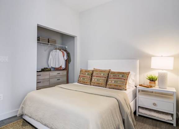A bedroom with a bed, nightstand, and closet.