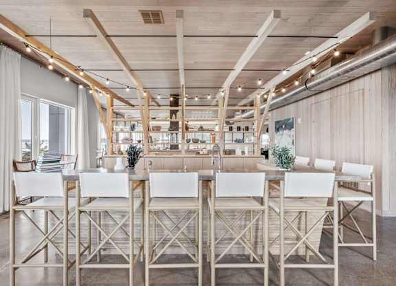 A long table with chairs is set up in a room with wooden beams on the ceiling.