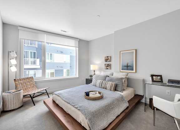 A bedroom with a large bed, a chair, and a desk.