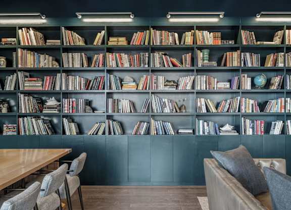 A room with a bookshelf filled with books and a table with chairs.