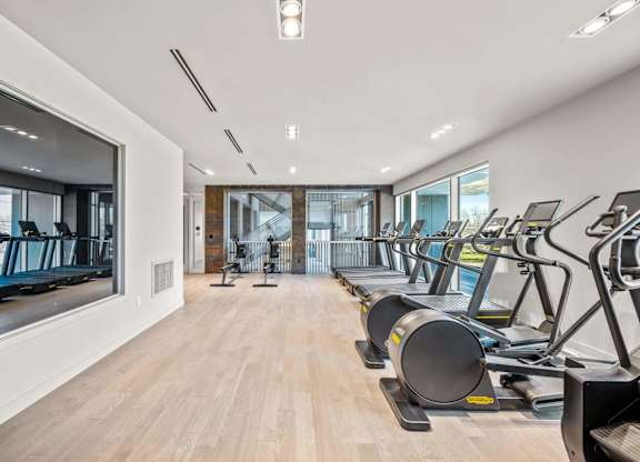 A gym with treadmills and a view of the outside.