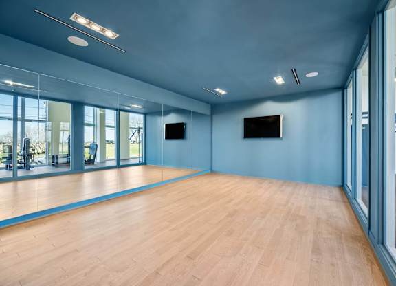 A spacious room with wooden floors and a television mounted on the wall.