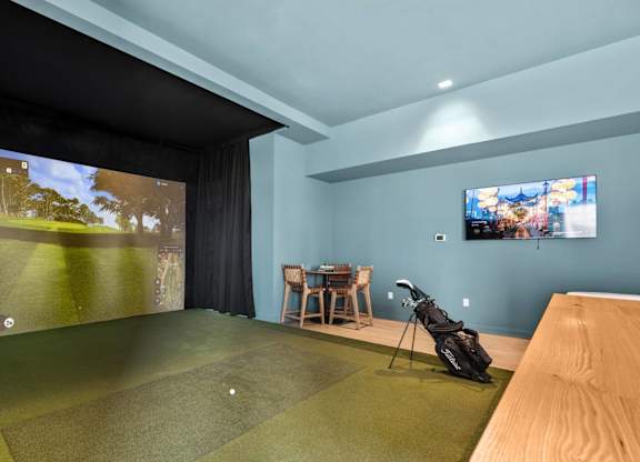 A golf simulator room with a screen showing a golf course.