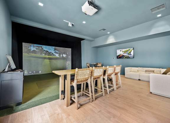A room with a table and chairs and a television on the wall.