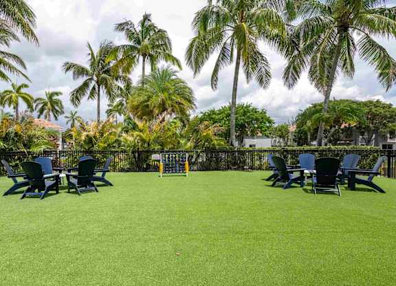 Community lawn at Polo Lakes with Adirondack chairs, palm trees, and outdoor games.