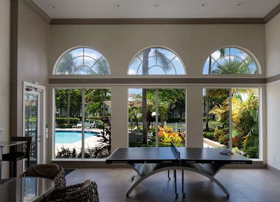 Game room at Polo Lakes with table tennis, arched windows, and pool views.