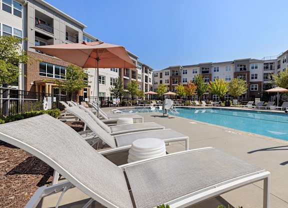 A sun lounger is in the foreground of a swimming pool.
