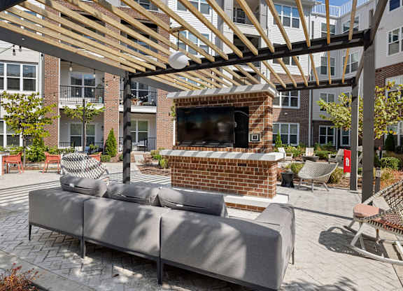 A patio with a couch and a television under a wooden roof.
