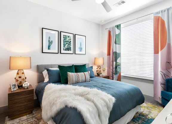 Apartment Bedroom with Window Coverings, Wall Art, and Overhead Ceiling Fan