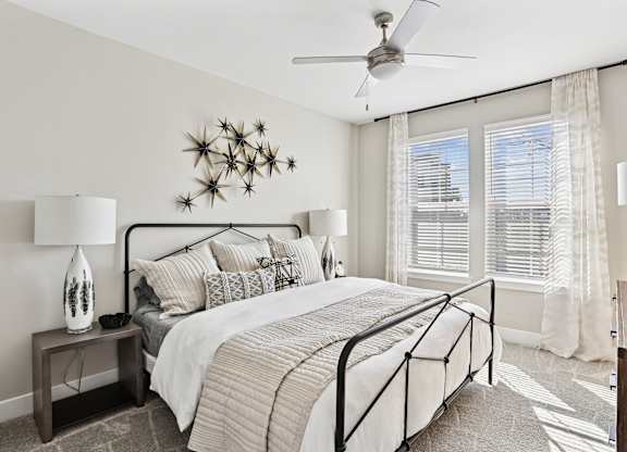 A bedroom with a large bed and a ceiling fan.