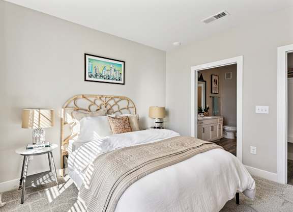 A bedroom with a large bed and a painting on the wall.