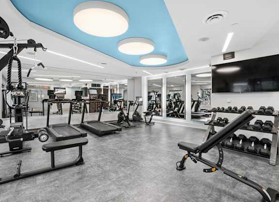 A gym with a variety of equipment including treadmills, weights, and exercise machines.