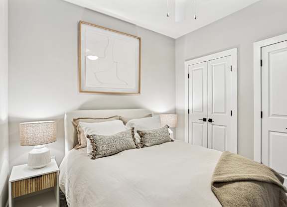 A bedroom with a bed, two lamps, and a picture on the wall.
