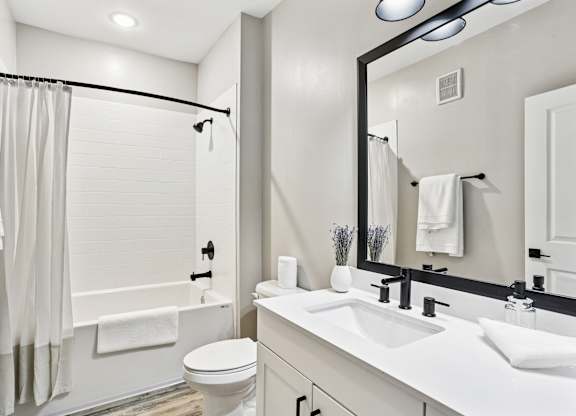 A white bathroom with a toilet, sink, and shower.