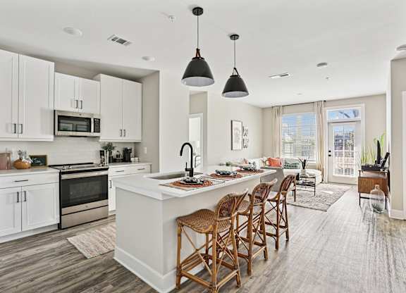 A modern kitchen with a large island and wooden chairs.