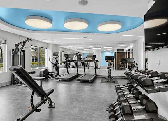 A gym with a variety of equipment including treadmills, weights, and exercise machines.