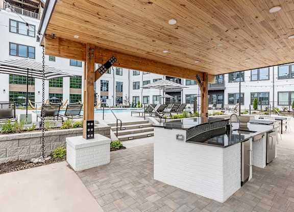 Full outdoor countertop with refrigerators under a modern pergola next to the pool at Novel Cary