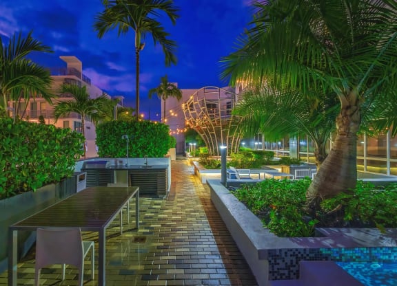 Palm-Lined Courtyard with Outdoor Kitchen and Dining Area at South of Atlantic