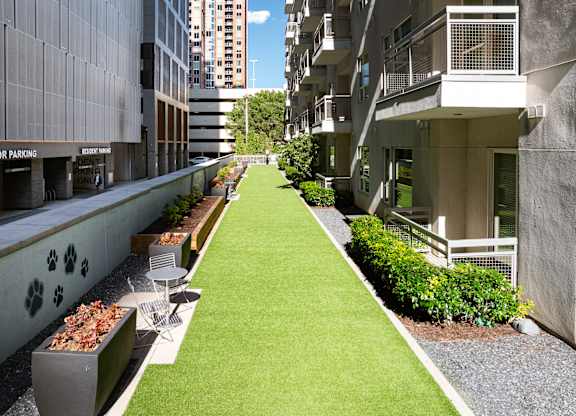 A long, narrow, grassy area separates two buildings.