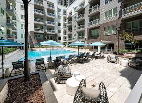 A large outdoor patio with a pool and chairs.