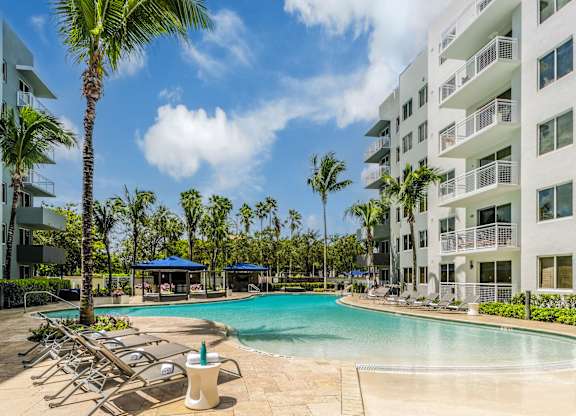 A swimming pool surrounded by palm trees and lounge chairs.