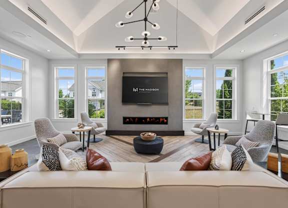 Clubhouse lounge with a modern fireplace, sectional sofa, armchairs, and large windows.