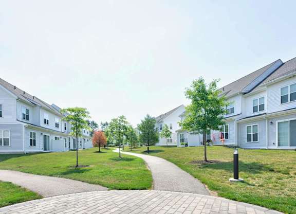 Curving paved path between residential buildings and landscaped lawn areas.