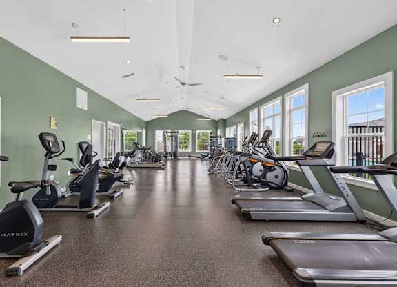 Fitness studio with cardio machines and large windows at The Madison at Marshfield.