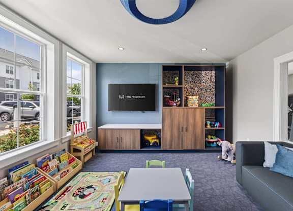 Indoor playroom with books, toys, child-size tables, and soft seating at The Madison at Marshfield.