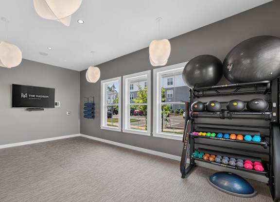 On-demand fitness room with a wall screen, exercise balls, weights, and balance equipment.