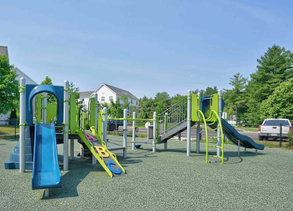 Colorful outdoor playground with two slides, climbing structures, and open play space.